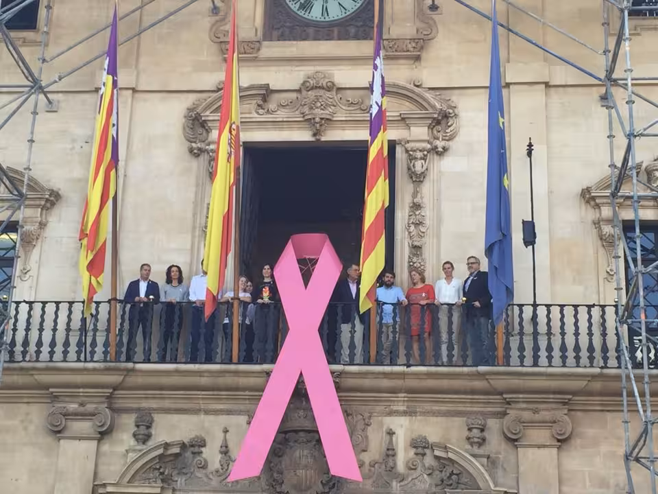 el ajuntament de palma cuelga un lazo rosa contra el cáncer en su fachada