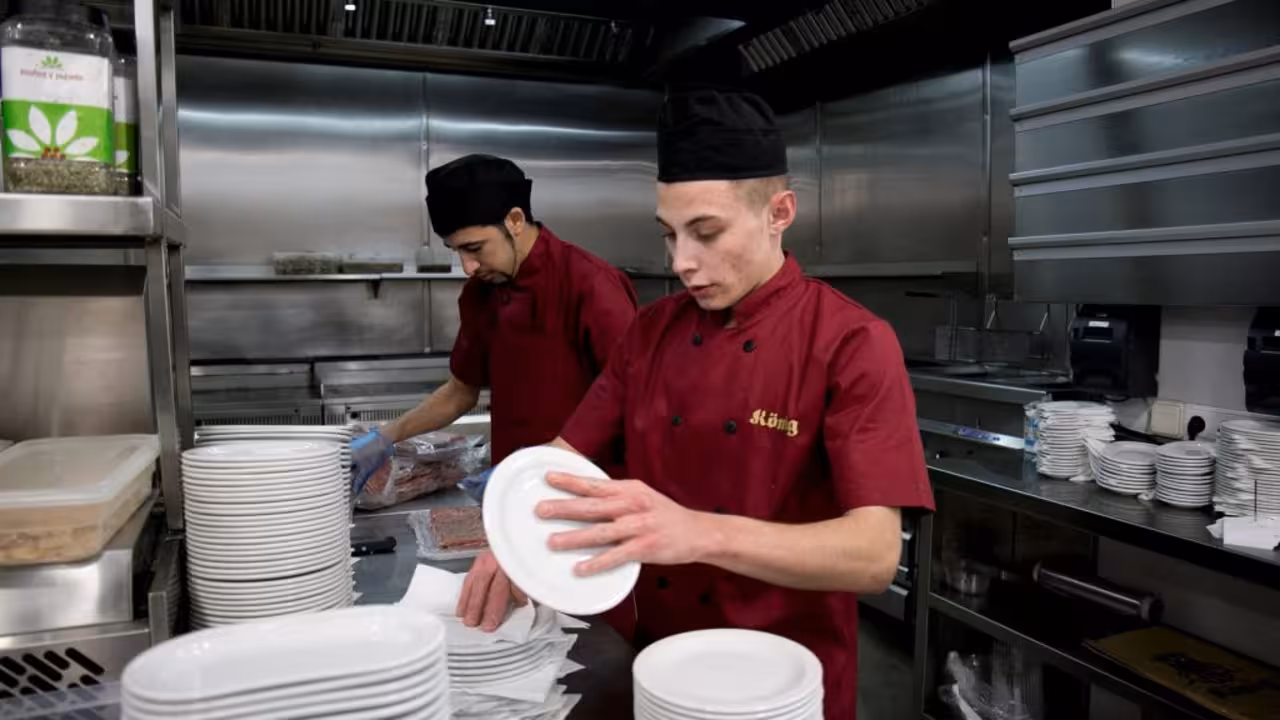 Joves beneficiaris del programa Incorpora treballant a la cuina d'un restaurant.